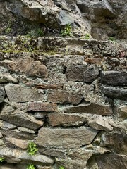 Close-up of an old stone wall with cracks, moss, and small plants. Useful for architecture, 3D modeling, restoration, history, and game design visuals.