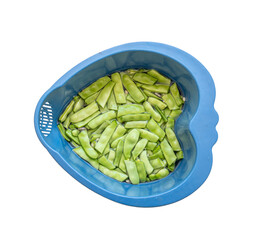 fresh green beans, cleaned for cooking. It is kept in water in a plastic blue basket.