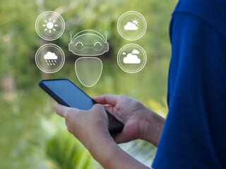 Person holding smartphone with weather forecast icons and robot assistant concept, outdoor background with green foliage, technology and communication theme