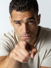 Fototapeta premium Serious Man Pointing at Camera with Intense Expression in Studio Light