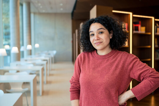 Confident woman with hand on hip in library