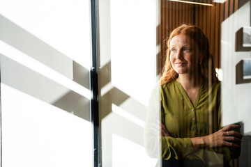 Red-haired woman smiling confidently in office setting