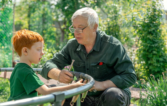 Grandfather and boy assembling a trampoline in the garden