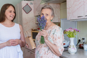 Senior woman smelling lavender flowers by granddaughter at home