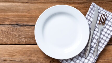 Empty white plate on a rustic wooden table with a checkered napkin and cutlery ready for a meal