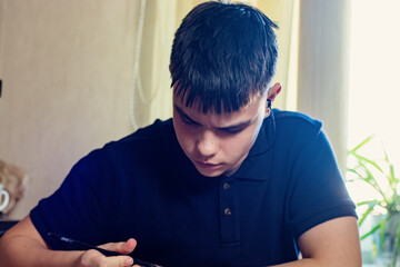 Young person with earbud and stylus focuses intently on a task indoors. Concept of learning, remote...