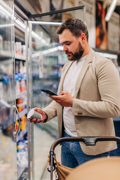 Father using mobile application to scan products in the dairy section of a supermarket