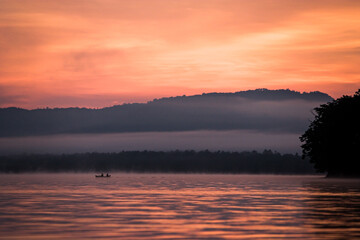 朝焼けと少し朝もやのかかった屈斜路湖を進む釣り船