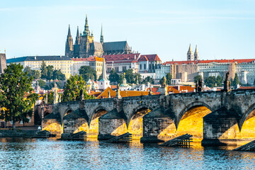 Early morning light casts a golden hue on Charles Bridge as it arches over the Vltava River. Prague...