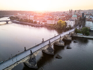 Golden morning light bathes Charles Bridge in Prague, highlighting its historic architecture and...
