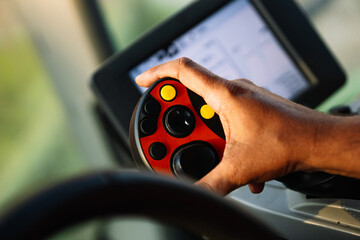Farmer controlling harvester with innovative joystick in tractor cab