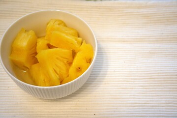Chopped pineapple in white bowl.