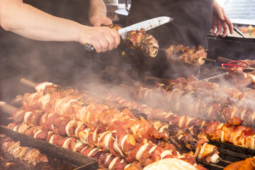 A man on the street fried on a large grill a lot of different meats and sausages during the street...