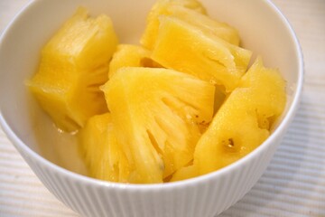 Chopped pineapple in white bowl.