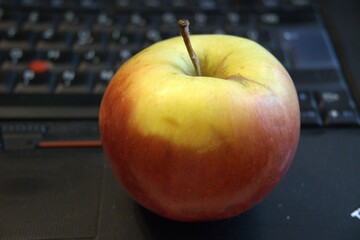 Healthy snack in work. One whole apple fruit with computer.