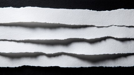 Close-up of torn white paper strips with black background textured surface.