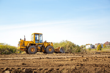 Yellow bulldozer at a construction site. Big wheel excavator leveling and clearing the land plot...