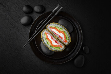 Creative sushi burger with rice and salmon on a textured black background. A modern fusion of...