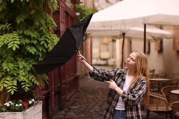 Woman with broken umbrella on city street