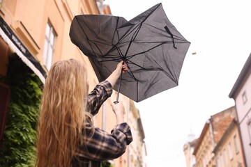 Woman with broken umbrella outdoors, low angle view