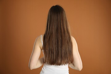 Woman with long hair on brown background, back view