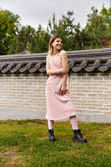 Girl in pink dress and boots smiles.