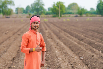 young indian farmer standing at agricultural field