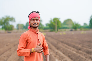 young indian farmer standing at agricultural field