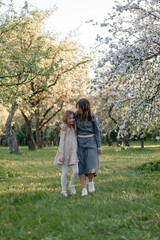 Fototapeta premium A mother and daughter are walking through a blooming apple orchard. they talk to each other. Concepts of family, mother and child, modern parenting.