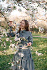 A delicate photo of a girl holding a blooming apple tree branch with white flowers in a sunny...