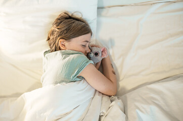 Child in a bedroom sleeps with a stuffed toy.