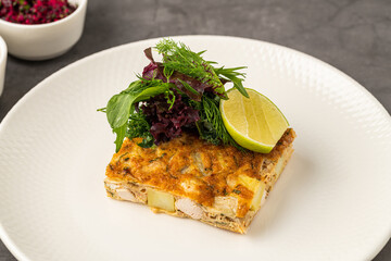 Spanish tortilla with potato and chicken, topped with fresh greens and lime