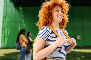 Student with diabetes enjoying a sunny day on campus while engaging in conversations and smiling as...