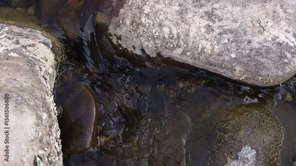 Poster slow motion of stream running over smooth rocks.