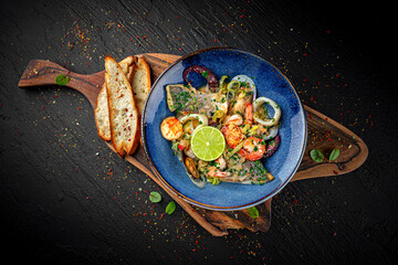 Luxury seafood salad with fish, shrimp, octopus, and mussels served with sauce on a dark background. Elegant gourmet dish.