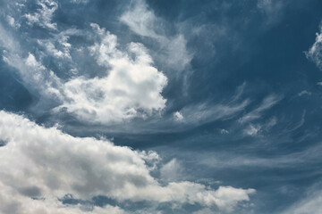 Fototapeta premium Bright blue sky with layered white clouds and wispy cirrus formations on a sunny day