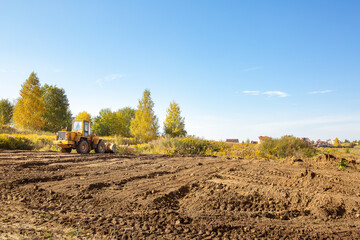 Yellow bulldozer at a construction site. Big wheel excavator leveling and clearing the land plot...
