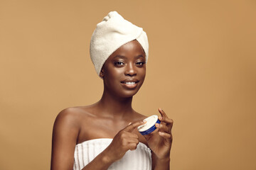 Beauty portrait of black woman holding blue cosmetic tin.