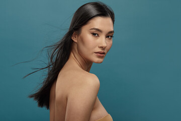 Well-groomed asian girl looking over shoulder to camera.