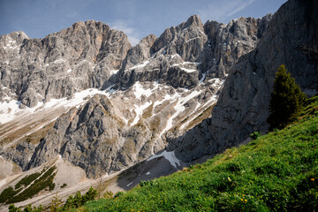 Dramatic Dachstein mountain peaks with lush green valley and clouds in Austria