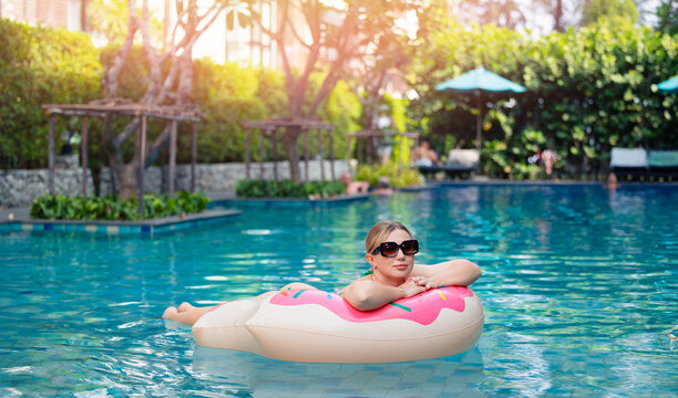 Young caucasian woman relaxing on inflatable float in sunny resort pool