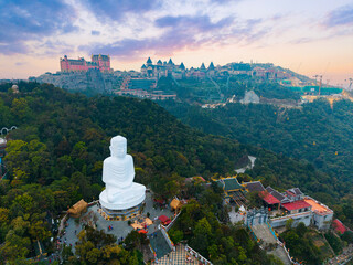 Aerial view of ba na hills at sunset featuring giant Buddha statue and lush greenery on background...