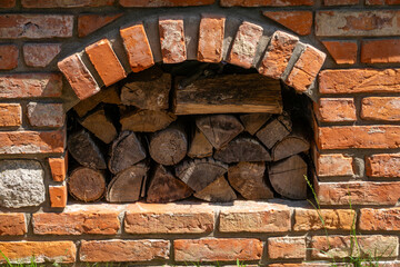 Stacked firewood in a brick wall niche with decorative arch – rustic outdoor detail