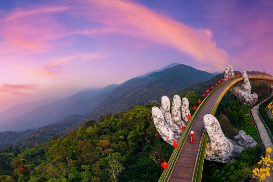 Aerial view woman tourist with traditional dress on Golden bridge at ba na hills in Da nang, Vietnam at sunset.