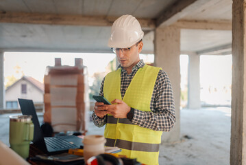Construction engineer using smartphone on site, managing projects and staying connected