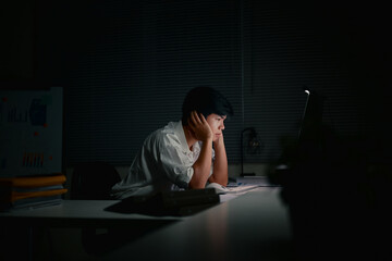 Exhausted businessman working late alone in a dark office