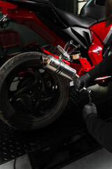 Obraz premium Exhaust Motorcycle System Maintenance. Mechanic tightening bolts on motorcycle chrome exhaust system for peak performance. Custom exhaust installation on red motorcycle enhances ride performance.