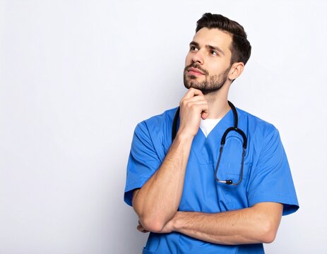 A thoughtful male healthcare professional in blue scrubs and a stethoscope is shown thinking deeply, likely contemplating a medical matter, in a studio or clean professional setting.