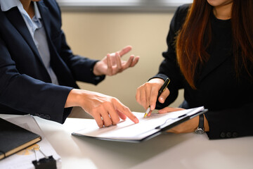 Two businesspeople pointing and discussing details on a document before signing