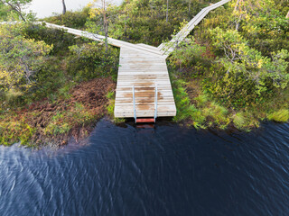 Aerial drone view of a wooden eco-trail with a ladder for swimming in a calm lake in a peat bog in...